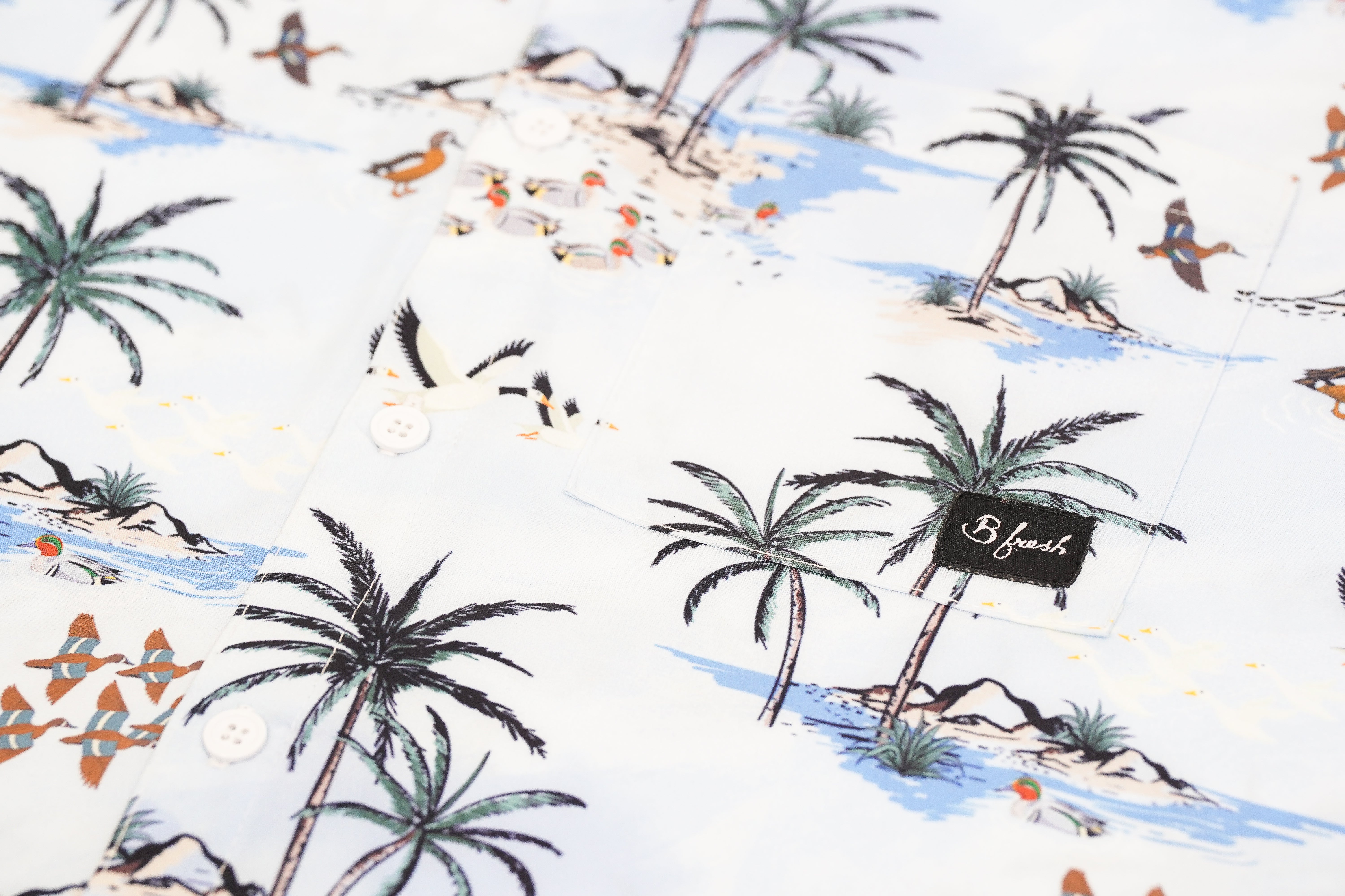 Fabric with a tropical pattern featuring palm trees and oasis scenes.
