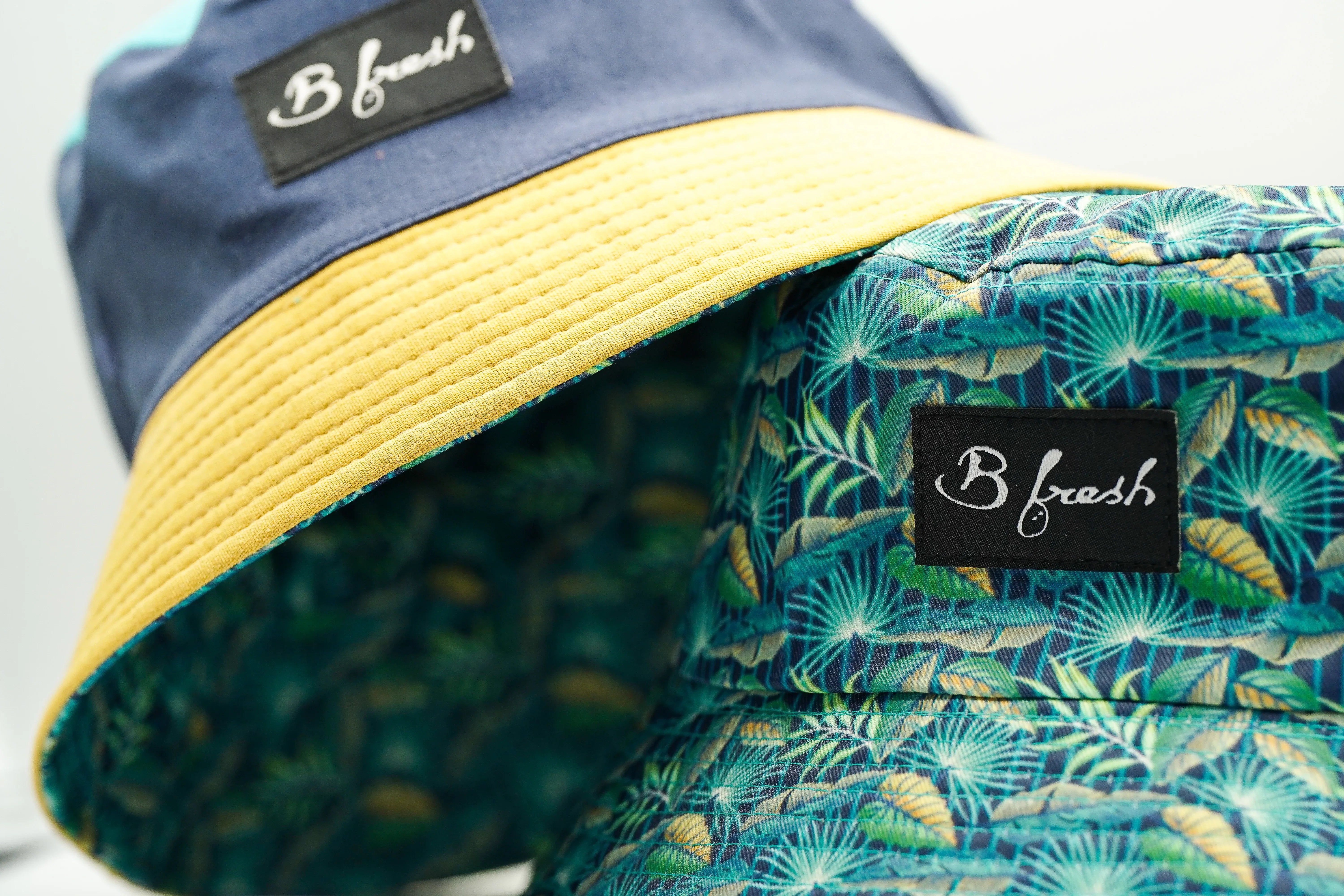 Bucket hat with yellow brim and tropical patterned fabric, featuring 'B fresh' branding.
