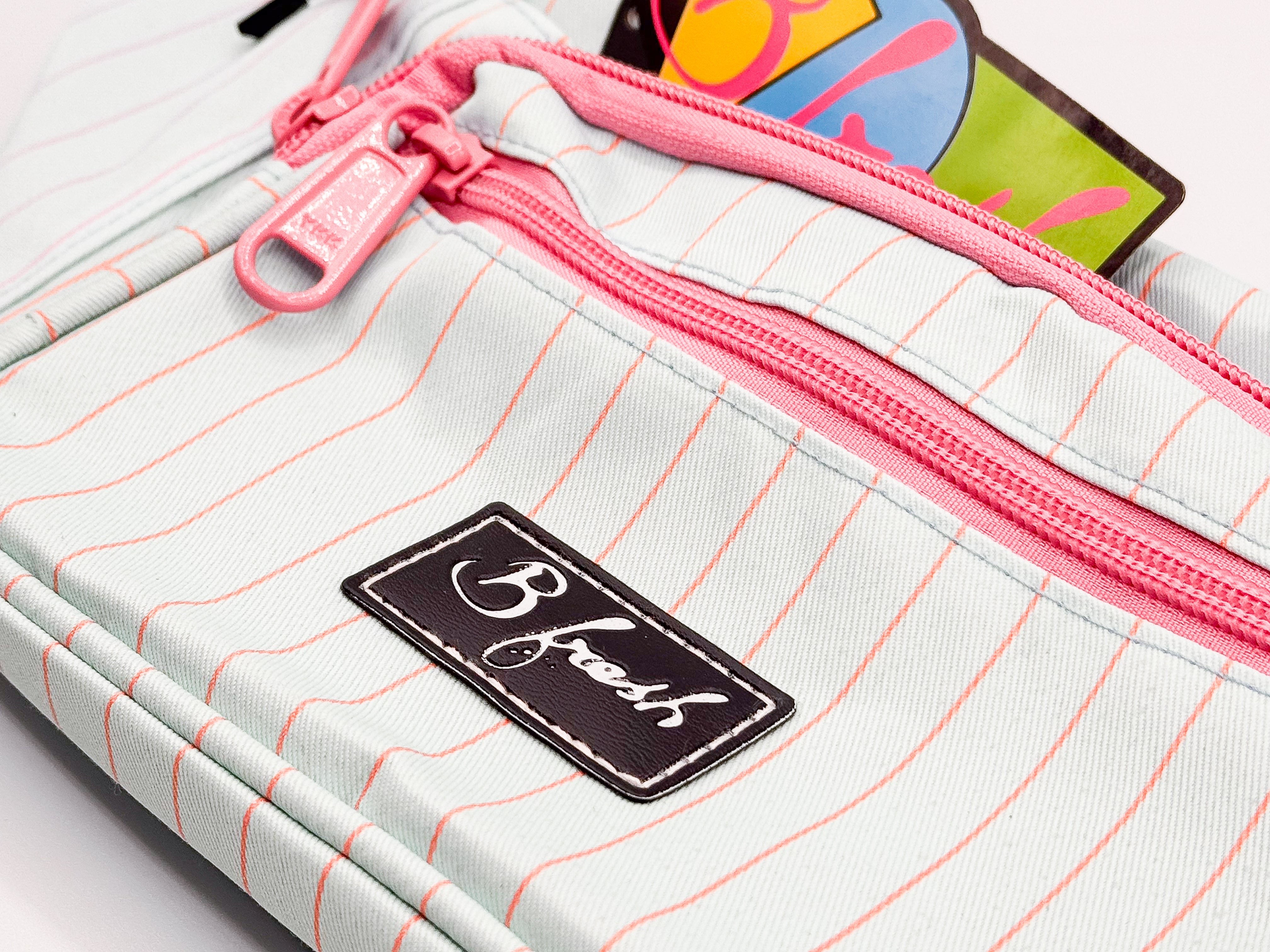 Pink zipper and 'B fresh' label on light blue bag