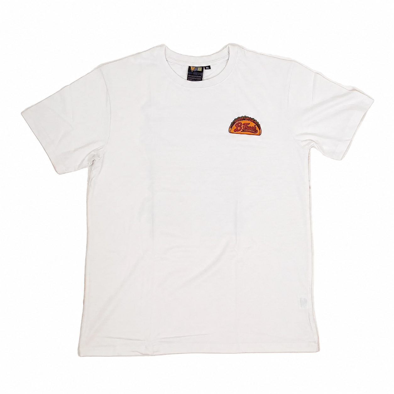 A white short-sleeve crewneck t-shirt laid flat on a textured off-white surface. It features a small orange and black graphic print on the left chest.