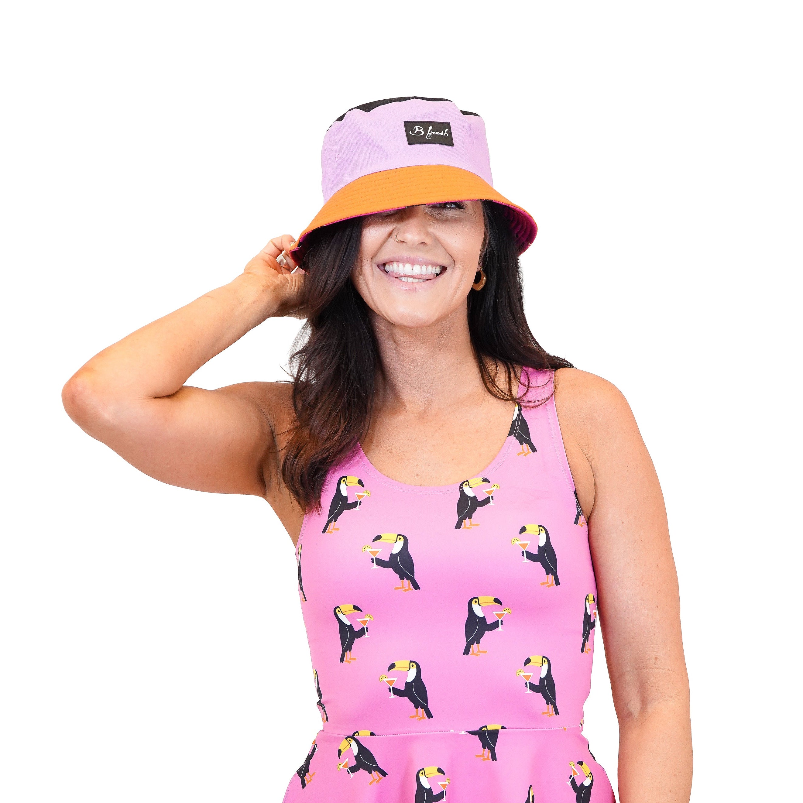 Woman wearing a pink bucket hat and pink dress with toucan patterns 