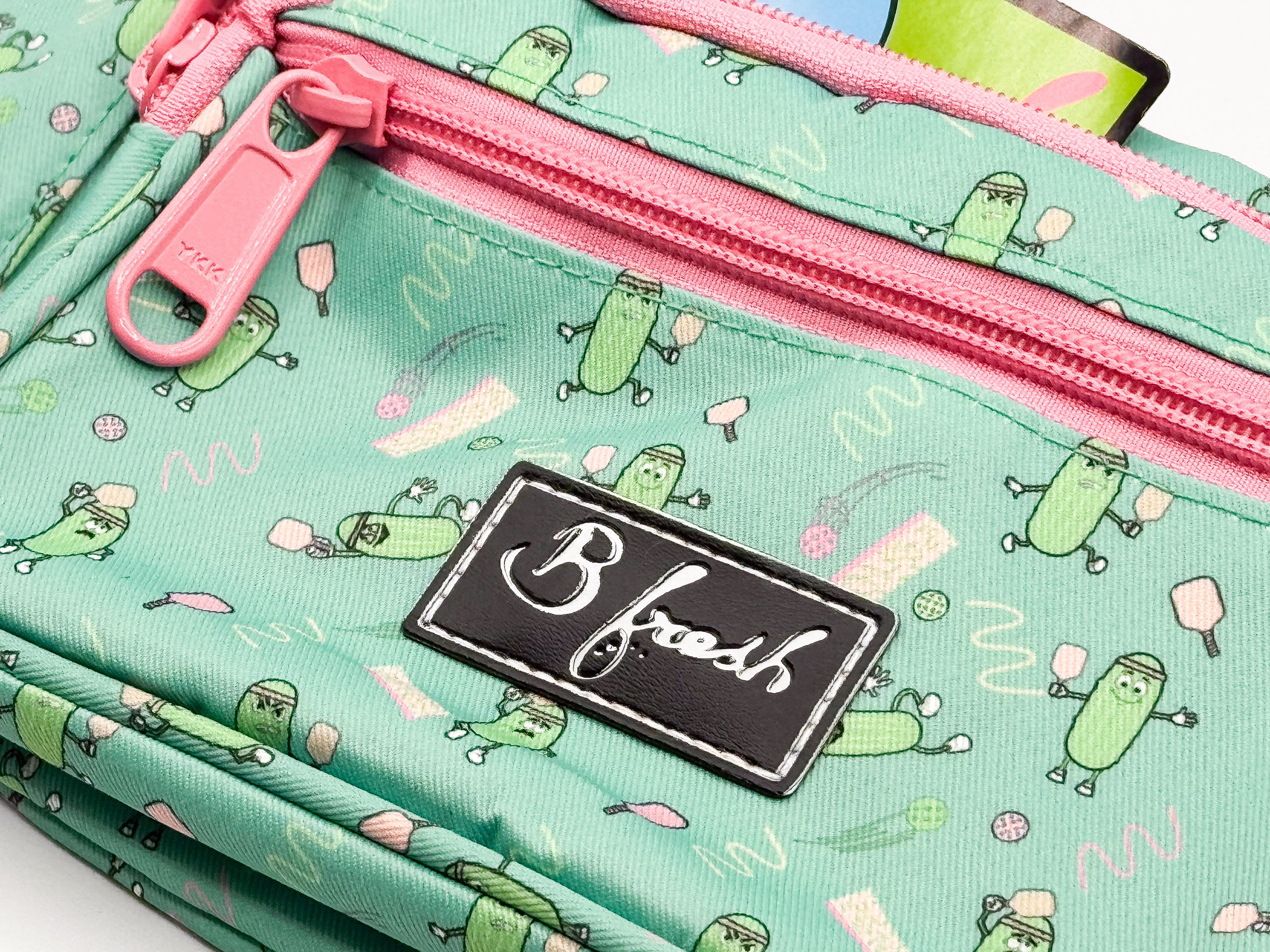 Green patterned bag with pink zipper and 'B fresh' label