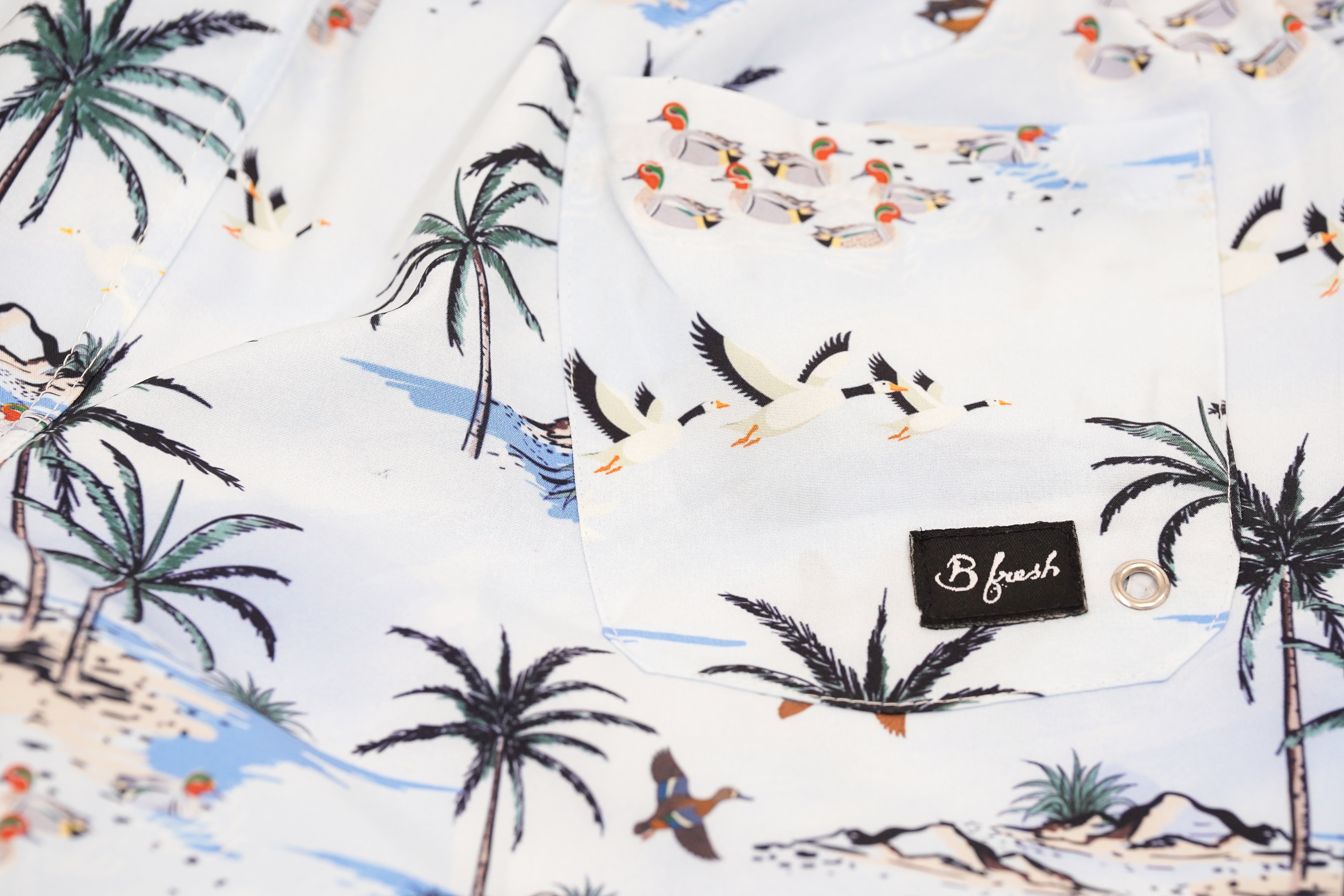 Shirt with beach-themed design featuring palm trees and ducks, branded 'B. fresh'.