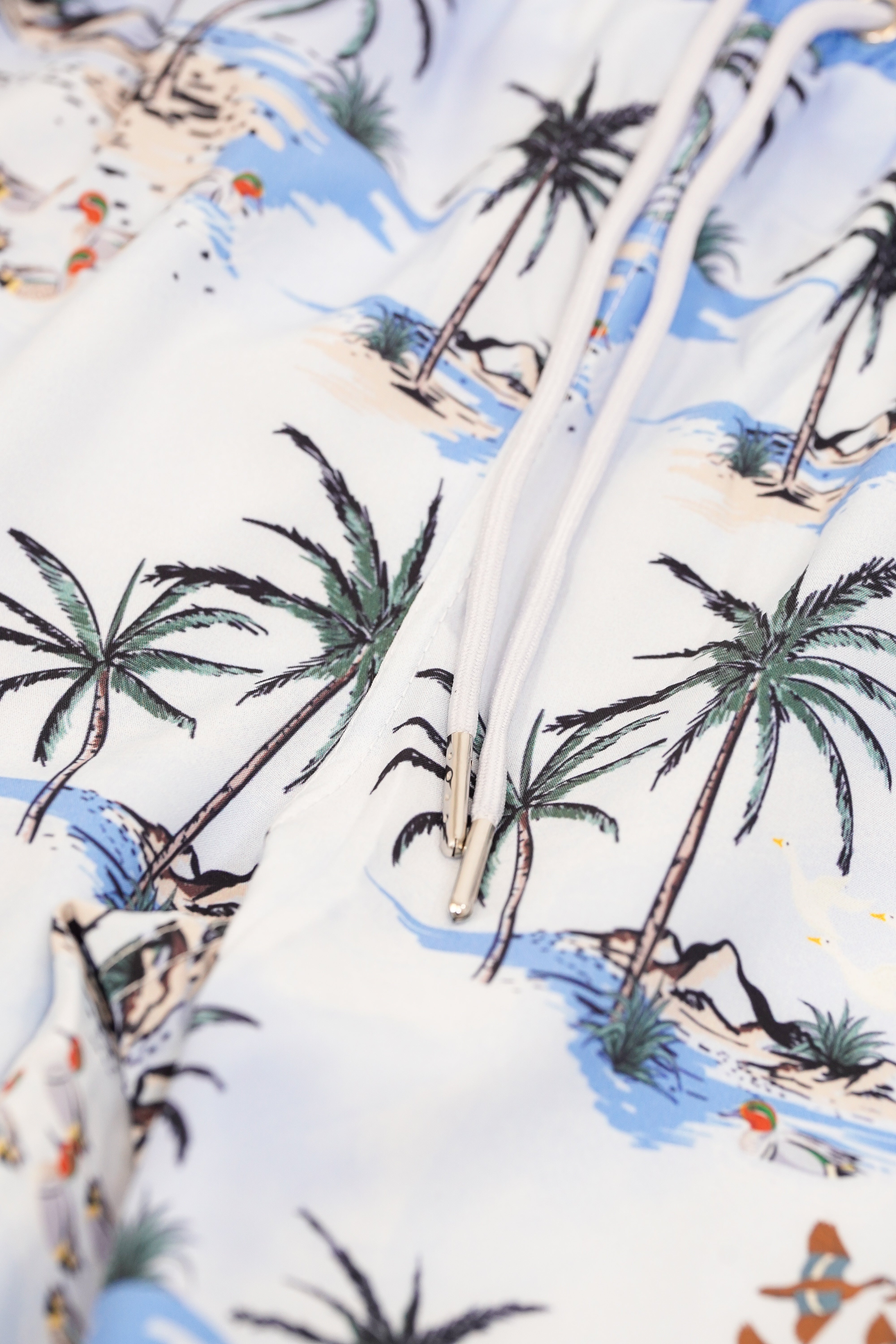 Close-up of a tropical-themed fabric with palm trees and beach scenes.