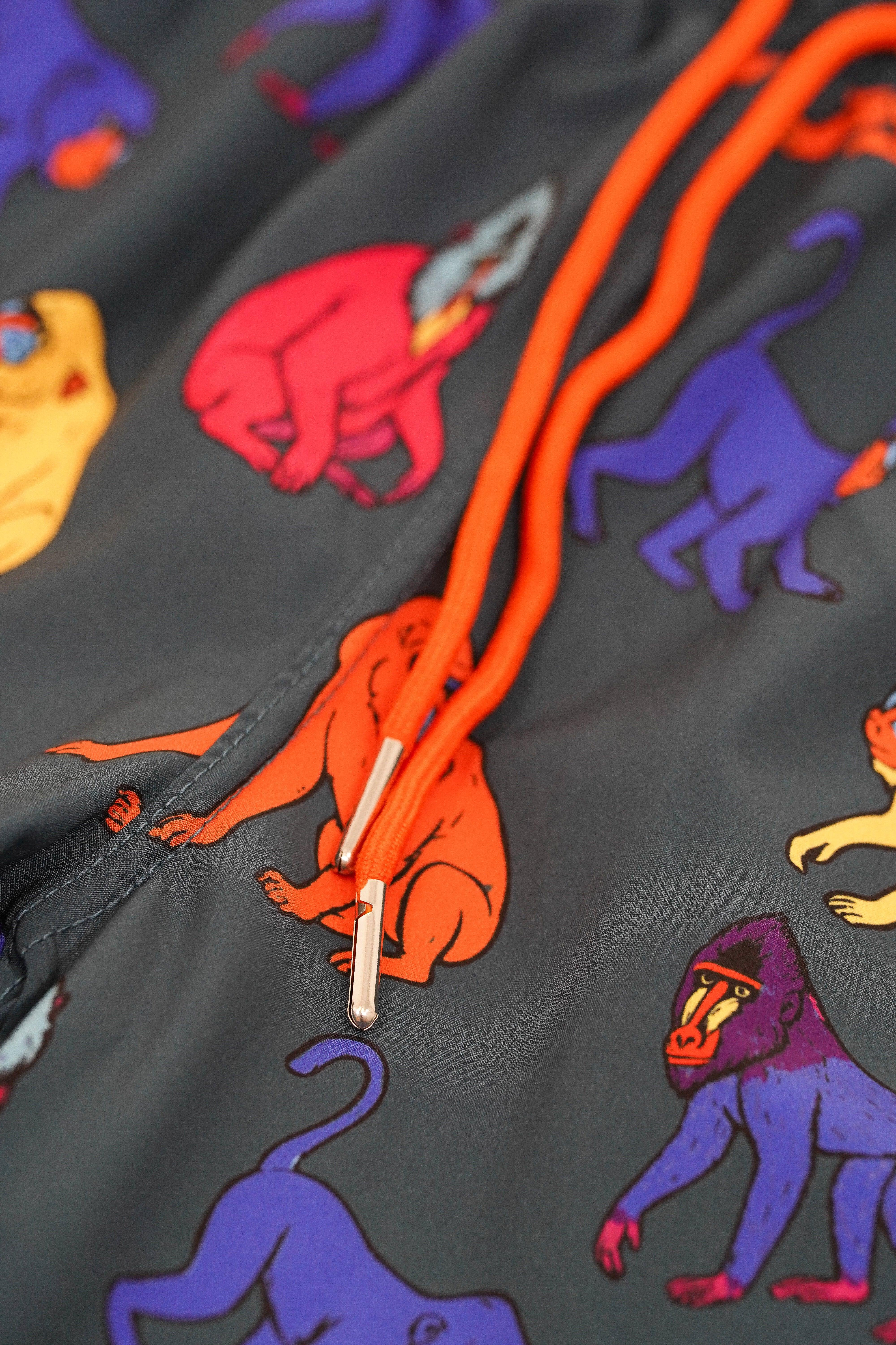 Close-up of a dark fabric with colorful monkey pattern and orange drawstring